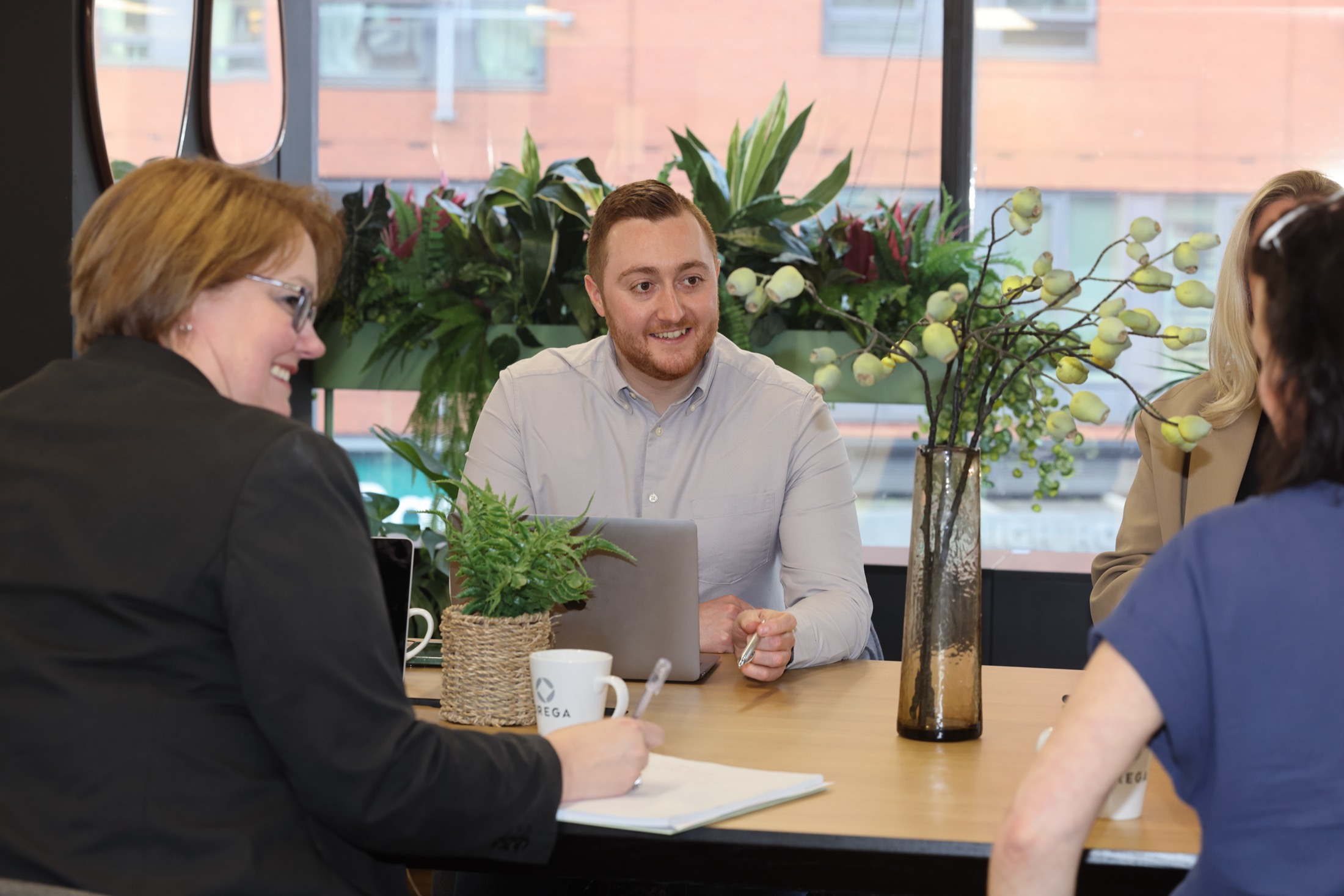 A friendly meeting around a table, notes being taken.